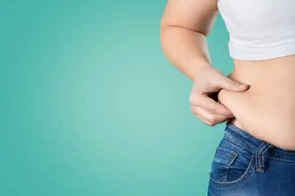 Image of woman pinching her love handles to show weight gain Teddington